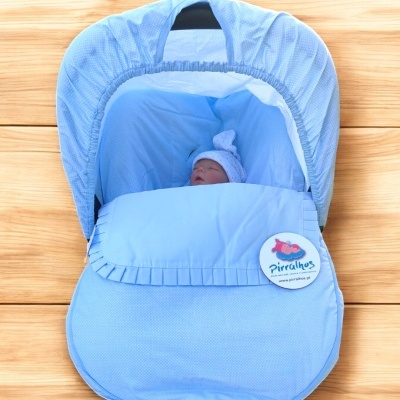 Berço portátil azul claro com boneco de bebé e botão Pirralhos