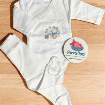 Conjunto de roupa de bebé branco com estampa de hipopótamo e ursinhos, etiquetas visíveis, sobre piso de madeira clara