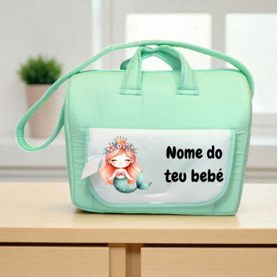Bolsa para bebê verde água com bolso branco e desenho de sereia, texto 'Nome do teu bebé', sobre superfície de madeira