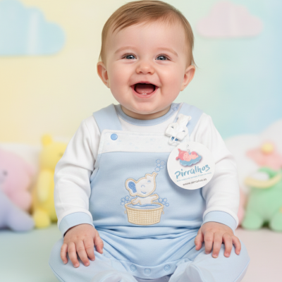 Bebé sorridente com macacão azul claro com bordado e etiqueta redonda sentado num fundo com peluches coloridos desfocados