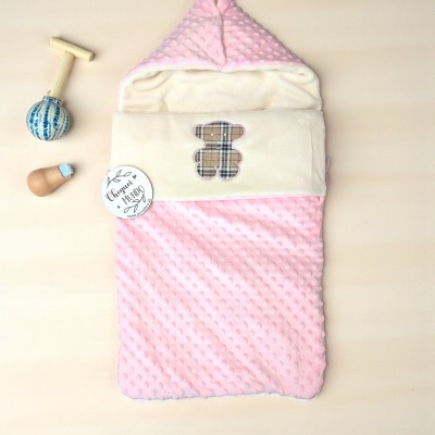 Saco de bebé cor-de-rosa com padrão bolinhas e ursinho xadrez, mais brinquedos em madeira