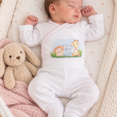 Bebé adormecido de pijama branco com estampa de animais e peluche coelho ao lado