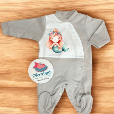Macacão de bebé cinzento e branco com estampa de sereia e botões de pressão, sobre madeira clara