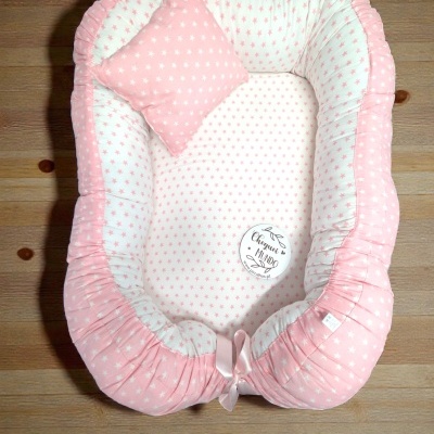 Ninho para bebé rosa e branco com estrelas e almofada em chão de madeira