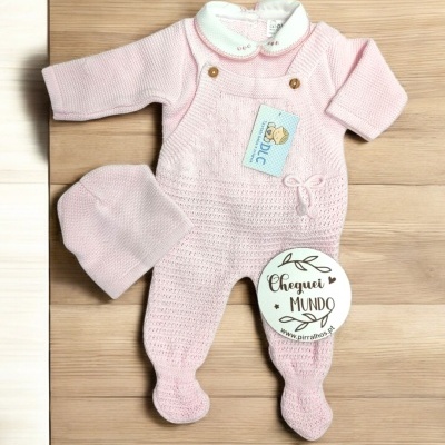 Conjunto de roupa de bebé rosa clara com macacão e gorro em malha, sobre fundo de madeira clara