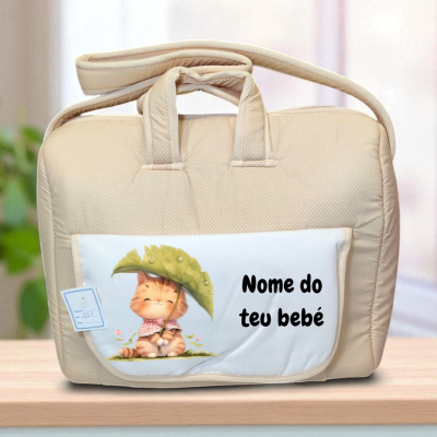 Mala de bebé bege com bolso branco e ilustração de gato e texto 'Nome do teu bebé'.