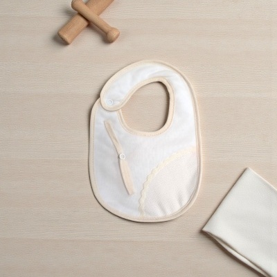 Babete branco com bordas bege e um brinquedo de madeira