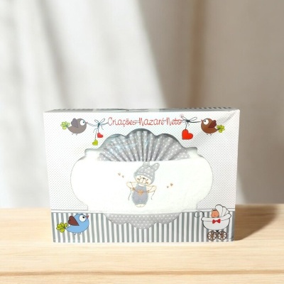 Caixa de tecido para bebé com ilustração e texto, sobre superfície de madeira