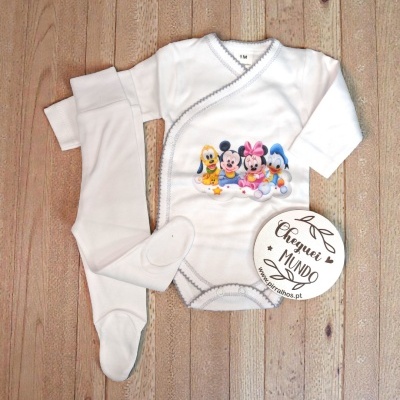 Conjunto de roupa de bebé branca com personagens Disney, mostrado sobre madeira.