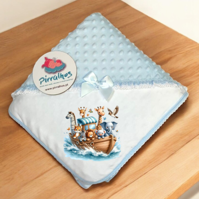 Manta azul para bebé com estampa de animais e etiqueta Pirralhos sobre mesa de madeira