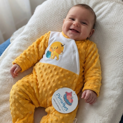 Bebé sorridente a usar macacão amarelo texturizado com personagem simba estampado