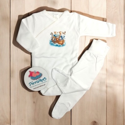 Conjunto roupa de bebé branco com ilustração de barco e animais sobre chão de madeira.