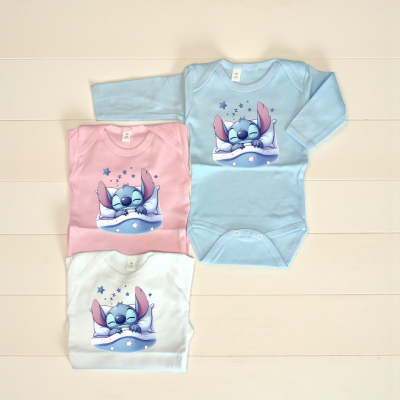Três bodys de bebé azul, rosa e branco com estampa de personagem azul a dormir.