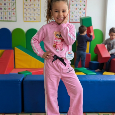 Menina com fato de treino rosa num parque infantil colorido