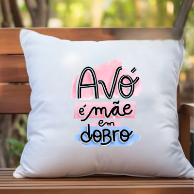 Almofada branca com texto colorido 'Avó é mãe em dobro' num banco de madeira ao ar livre