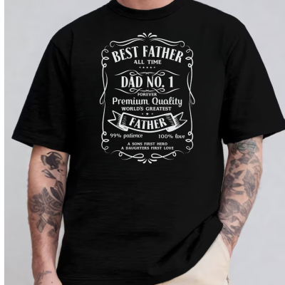 Camiseta preta com texto branco sobre paternidade e tatuagens nos braços do modelo