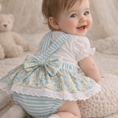 Bebé sorridente de vestido floral azul com laço e meias brancas, em ambiente interior acolhedor