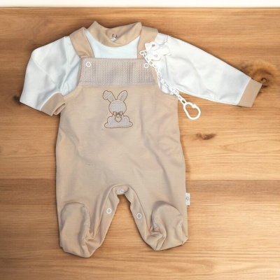 Fato de bebé creme e bege com bordado de coelho colocado sobre madeira