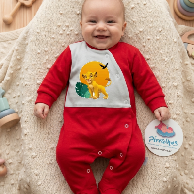 Bebé com body vermelho e branco com estampa de leão amarelo, deitado numa manta bege com brinquedos de madeira
