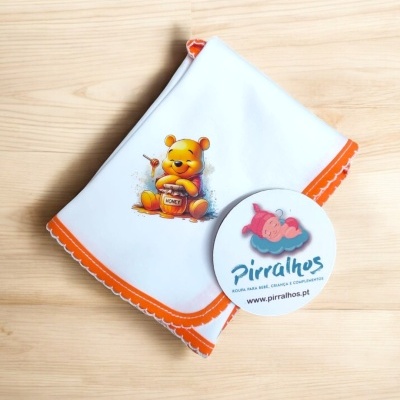 Fralda branca com imagem do ursinho Pooh e borda laranja sobre madeira clara