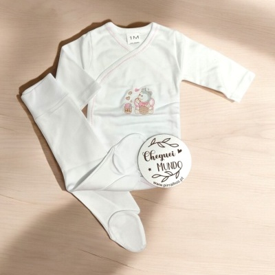 Conjunto de roupa branco para bebé com bordado de urso e etiqueta redonda sobre madeira clara