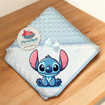 Manta de bebé azul com personagem Stitch e etiqueta Pirralhos sobre madeira