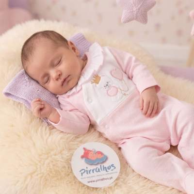 Bebé a dormir com fato cor-de-rosa e almofada peluda creme