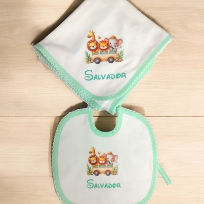 Babete e fralda brancos com bordas verdes e estampas de animais com o nome Salvador