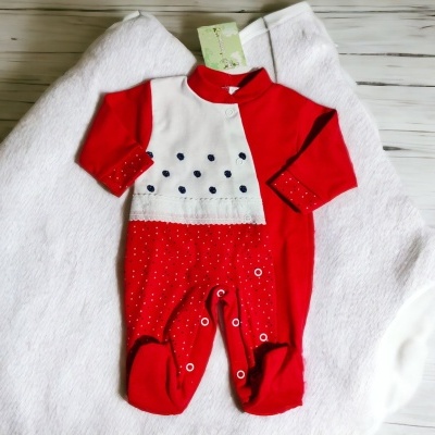 Macacão vermelho e branco para bebé com bolinhas, sobre cobertor branco