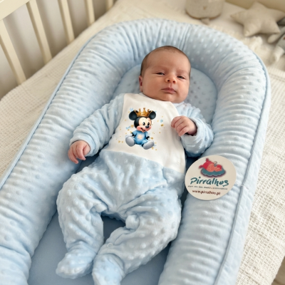 Ninho para bebé azul claro com bebé vestido de pijama azul e estampa do Mickey Mouse.