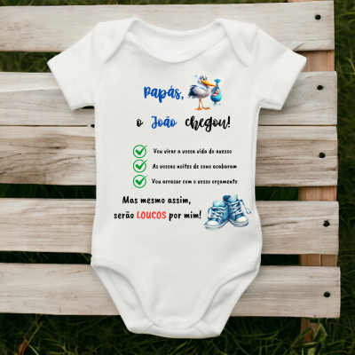 Body de bebé branco com texto e ilustrações coloridas sobre banco de madeira.