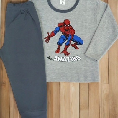 Pijama infantil cinzento com estampa do Homem-Aranha e calças azul escuras sobre chão de madeira