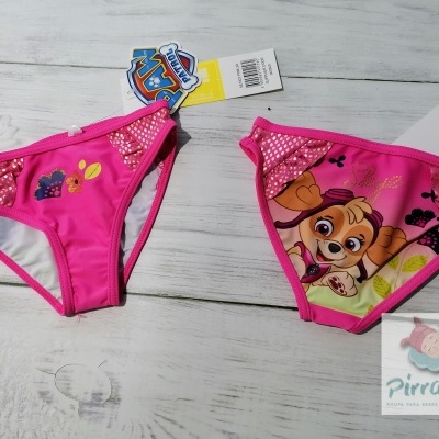 Biquinis infantis cor-de-rosa com personagem animado e padrões coloridos sobre superfície de madeira clara