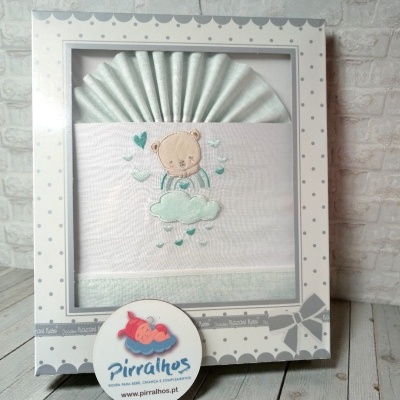 Conjunto de roupa de bebé com bordado de urso numa caixa decorada