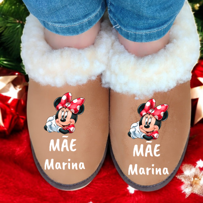 Chinelos castanhos felpudos com Minnie Mouse e texto MÃE Marina, usados com jeans azuis, sobre tapete vermelho natalício.