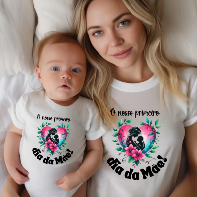 Mãe e bebé deitados com camisetas brancas estampadas com design colorido e texto 'O nosso primeiro dia da Mãe!'.
