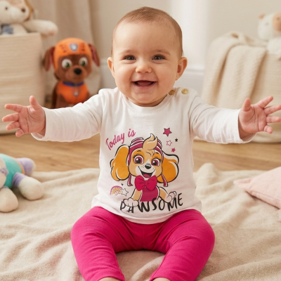 Bebé sorridente sentado com roupa colorida num quarto acolhedor.