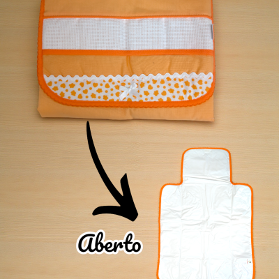 Muda-fraldas portátil laranja fechado e aberto sobre fundo de madeira