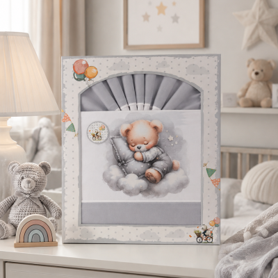 Caixa com roupa de bebé azul e ursinho a dormir embalada, sobre uma cómoda com decoração infantil.
