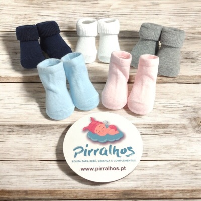 Cinco pares de meias de bebé em várias cores sobre madeira com cartão publicitário da Pirralhos