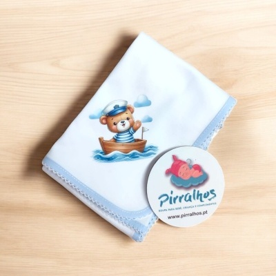 Fralda branca com urso marinheiro e etiqueta da marca Pirralhos