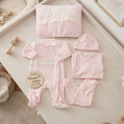 Conjunto de roupa de bebé cor-de-rosa com babygrow, calças, casaco, chapéu e manta em mesa branca de madeira