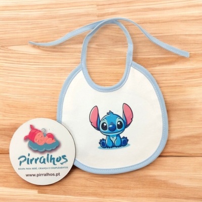 Babete branco com desenho azul do Stitch e selo redondo da marca Pirralhos em madeira clara