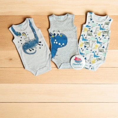 Três bodies de bebé com desenhos de dinossauros em madeira clara