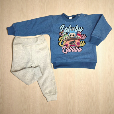 Conjunto infantil azul com estampado e calças cinza claras sobre madeira clara