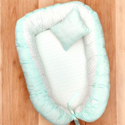 Ninho de bebé azul claro com almofada sobre chão de madeira