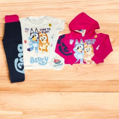 Conjunto infantil com camisola branca, calças azul escuro e casaco rosa com estampados de personagens e texto
