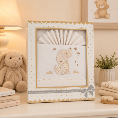Conjunto de roupa de bebé branco com bordado de cachorro em caixa decorativa sobre móvel creme