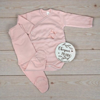 Conjunto de bebé cor-de-rosa com detalhes e placa CHEGUEI MUNDO sobre madeira clara.