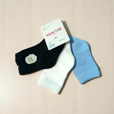 Três pares de meias para bebé nas cores preta, branca e azul clara com etiqueta YANOIR 0-6